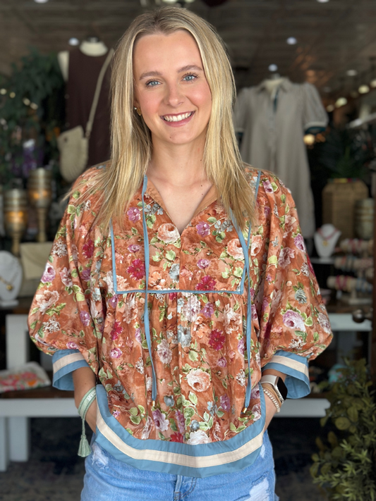 Woman wearing a floral blouse with a blurred indoor background
