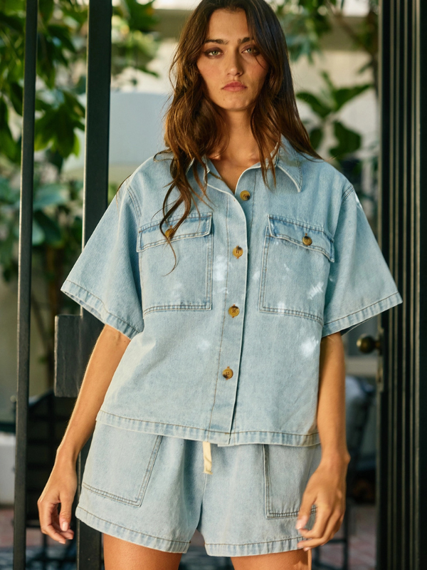 Woman wearing a light blue denim outfit with a blurred outdoor background