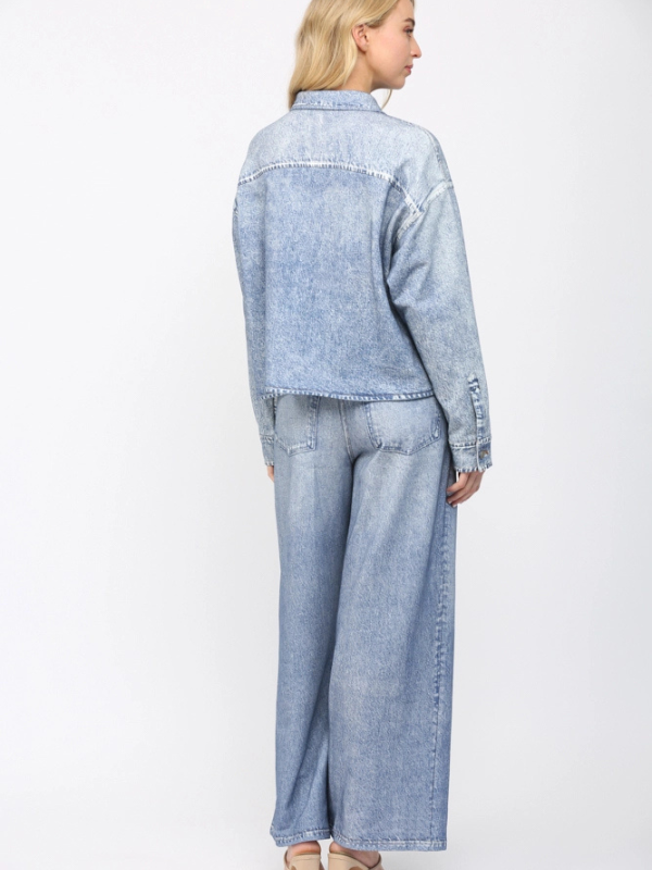Person wearing a light blue denim jacket and pants on a white background