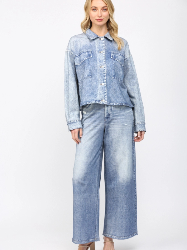 Woman wearing a light blue denim jacket and jeans on a white background