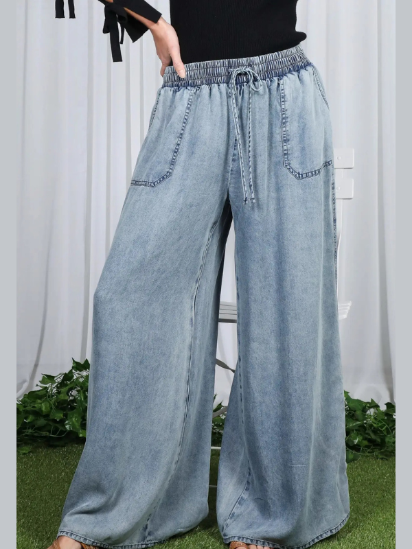 Light blue denim wide-leg pants worn by a person against a white curtain background.