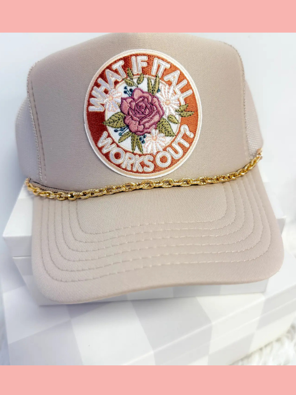 Beige trucker hat with floral patch and gold chain on a white background