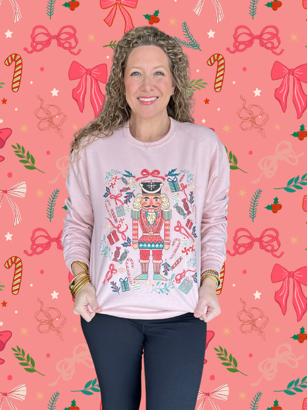 Woman wearing a pink sweater with a nutcracker design on a festive background