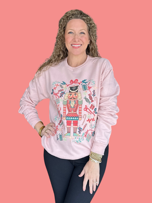 Woman wearing a pink sweatshirt with a colorful design on a pink background