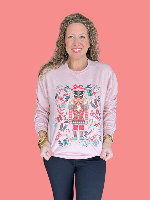 Woman wearing a pink sweatshirt with a colorful design on a coral background