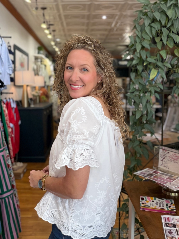 Woman wearing a white lace top in a store setting