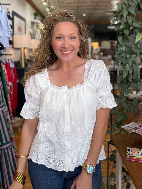 Woman wearing a white lace top in a store setting