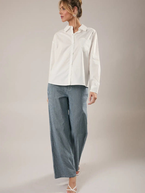 Woman wearing a white shirt and blue checkered pants on a plain background