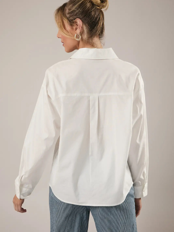 Woman wearing a white shirt and striped pants on a plain background