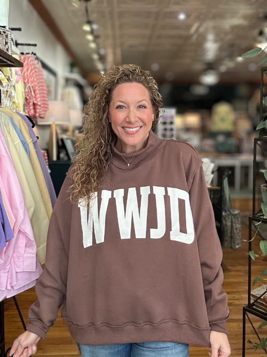 Woman wearing a brown sweatshirt with 'WWJD' in a store setting