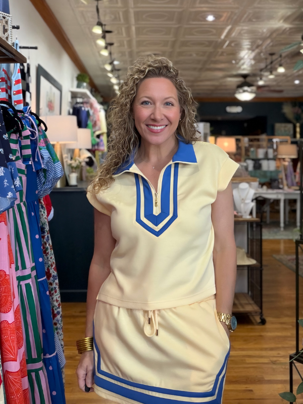 Woman wearing a vintage-style outfit with a blue and white top and skirt in a store setting.