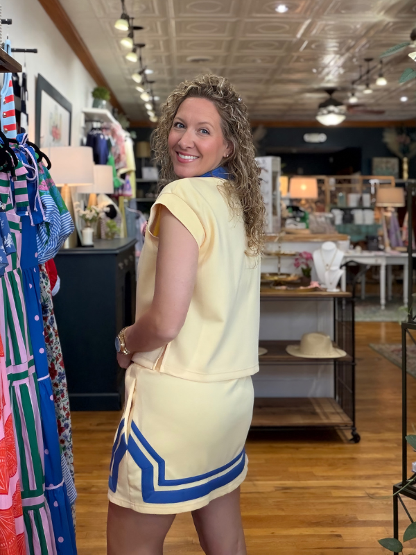 Woman in a yellow dress with blue accents standing in a store.
