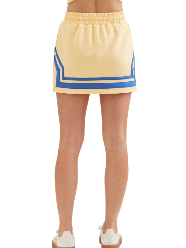 Beige skirt with blue trim worn by a person on a white background