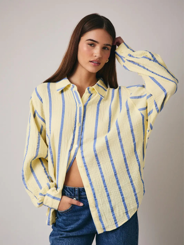 Woman wearing a yellow and blue striped shirt against a plain background