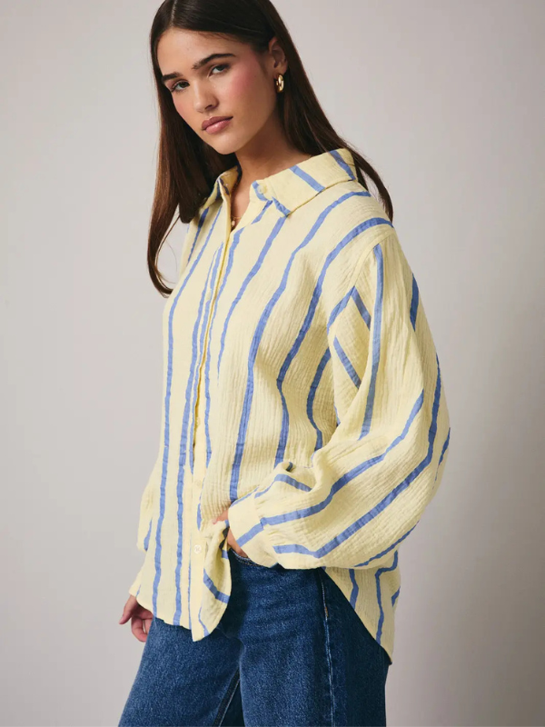Woman wearing a yellow and blue striped shirt against a plain background