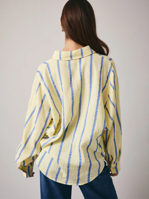 Person wearing a yellow and blue striped shirt against a plain background