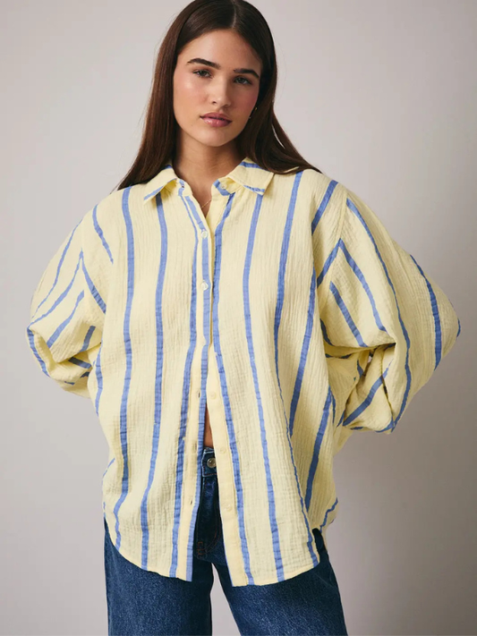 Woman wearing a yellow and blue striped shirt against a plain background