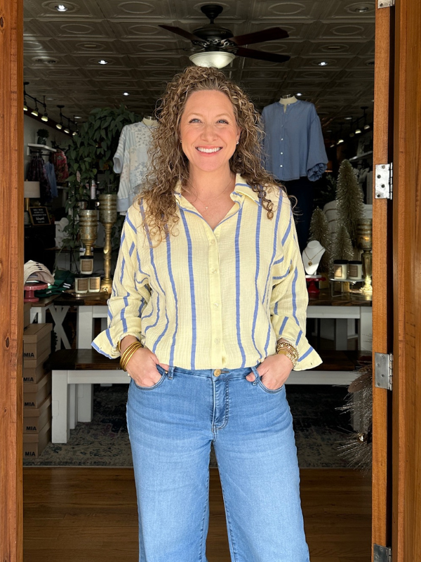 Woman wearing a yellow striped shirt and blue jeans standing in a store.