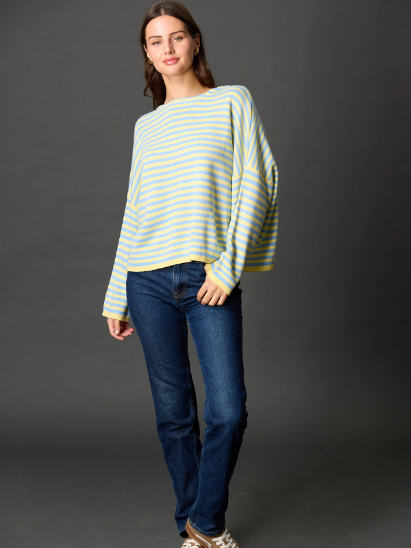 Woman wearing a striped sweater and jeans against a gray background