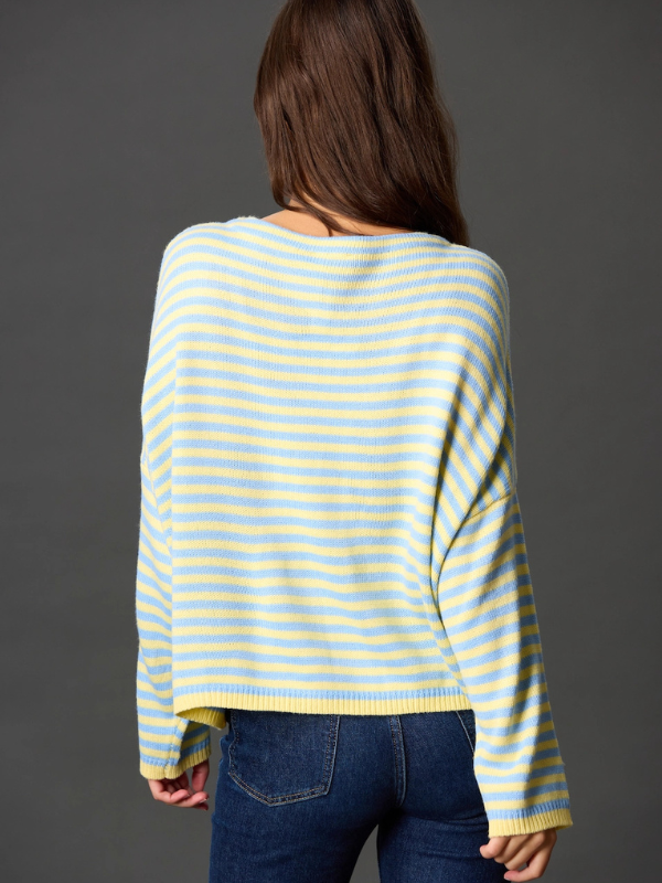 Person wearing a yellow and blue striped sweater against a gray background