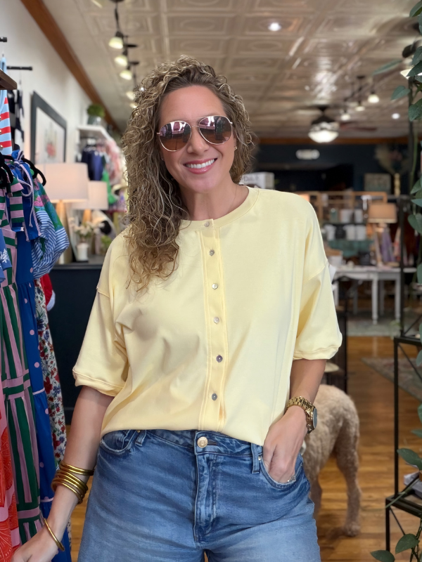 Woman wearing a yellow blouse and sunglasses in a store setting