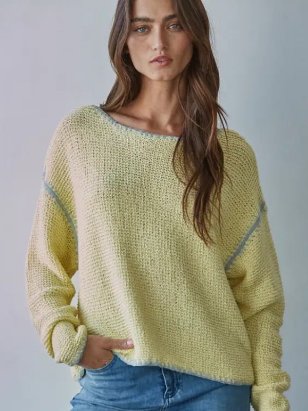 Woman wearing a light green sweater with blue jeans against a plain background
