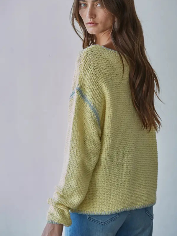 Woman wearing a light green sweater with a subtle pattern on a plain background