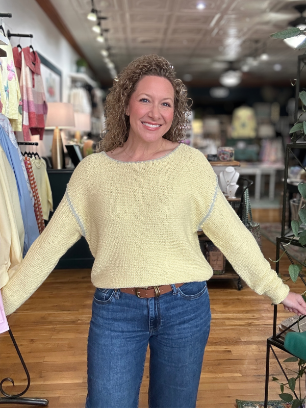Woman wearing a yellow sweater and blue jeans in a store setting