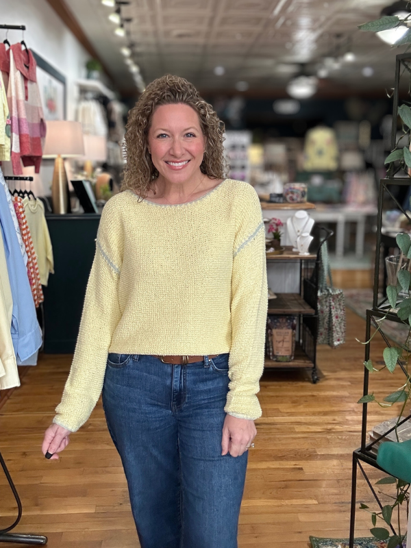 Woman wearing a yellow sweater and blue jeans in a store setting