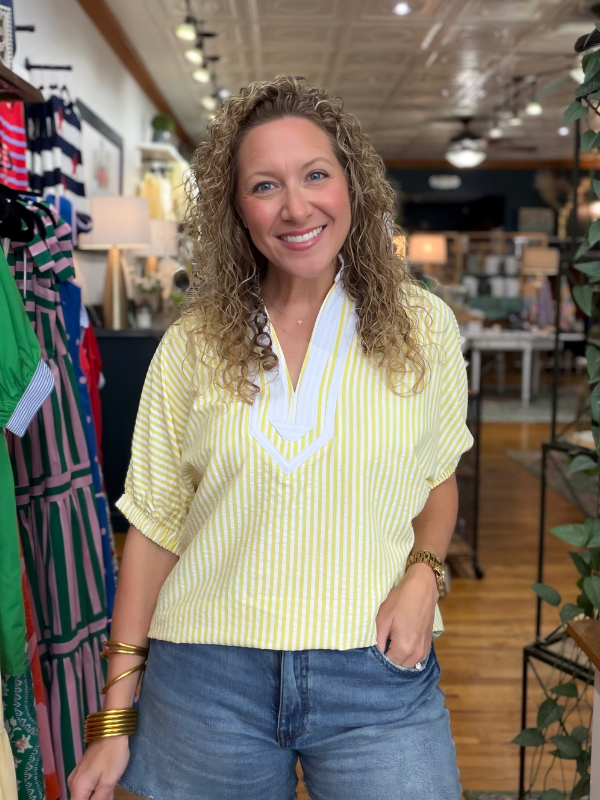 woman wearing a yellow and white striped top in a store 