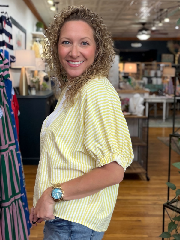 woman wearing a yellow and white striped top in a store 