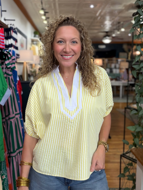 woman wearing a yellow and white striped top in a store 