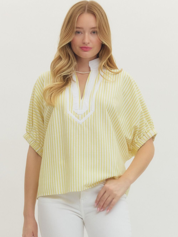 Woman wearing a yellow striped blouse with a white collar on a plain background