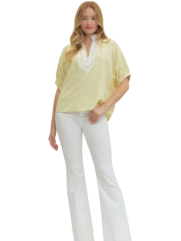 Woman wearing a yellow blouse with a white collar and white pants on a white background